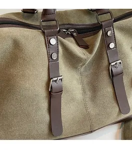 Detail of durable olive canvas travel bag with premium brown leather straps and metal buckles