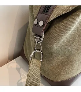Detail of olive green canvas travel bag with premium leather trim and silver metal hardware