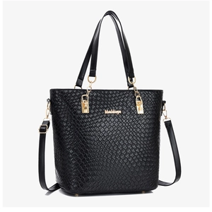 Close-up of black tote bag featuring embossed woven texture and gold chain straps