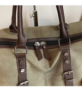 Close-up of smooth metal double zippers and leather accents on an olive green travel bag