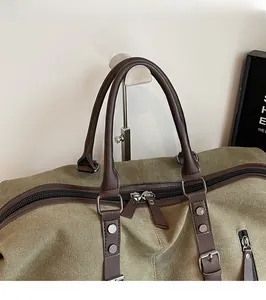 Detail of the olive green canvas travel bag featuring leather handles and metal rivets