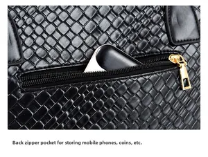 Detail of the back zipper pocket on the black woven tote bag containing a smartphone
