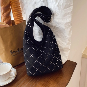 Black suede hobo bag with silver studs and diamond pattern in a lifestyle setting