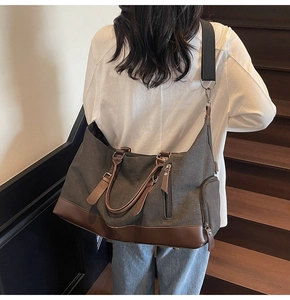 Detail view of large canvas travel bag with leather accents showing side zip compartment