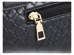 Close-up of golden zipper on black woven leather tote bag showing high-quality detail