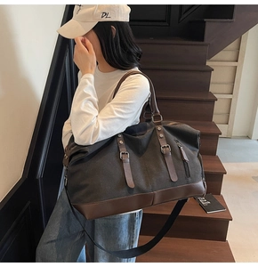 Detail of grey canvas travel bag with brown leather accents on a wooden staircase