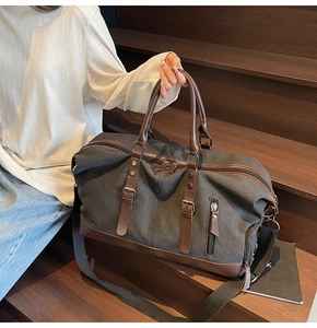 Detail of canvas travel bag with brown leather trim on dark wooden stairs