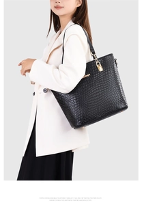 Close-up of black embossed tote bag with gold padlock detail and woven texture leather