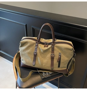Detail of army green canvas travel bag with brown leather trim on a black chair