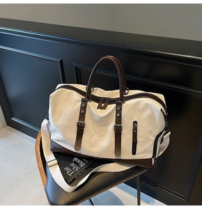 Close-up of large canvas travel bag with leather accents on a dark seat