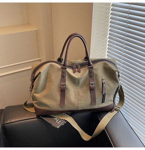 Close-up of olive green canvas travel bag with dark brown leather straps and dual zippers