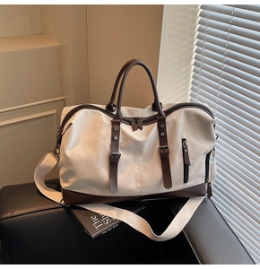 Detail of canvas travel bag with leather accents on a dark surface in natural light