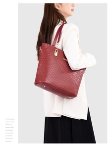 Deep red tote bag with embossed woven pattern and golden hardware shown on shoulder