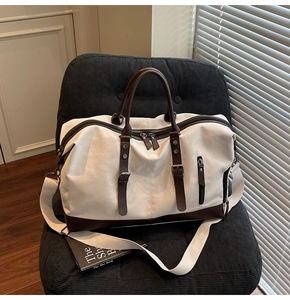 Close-up of large canvas travel bag with brown leather handles on a chair