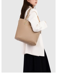 Close-up of khaki croc-embossed tote bag with gold lock charm on a female model