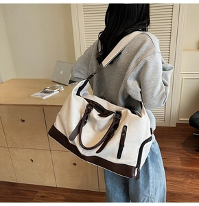 Detail of canvas travel duffle bag with leather trim showing side zipper pocket