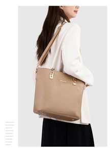 Close-up of brown embossed tote bag featuring gold buckle details and luxury texture