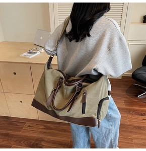 Detail of olive green canvas travel bag with brown leather handles and vertical zipper pockets