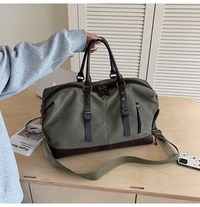 Detail of large olive green canvas travel bag with brown leather base and adjustable strap
