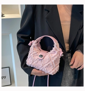 Dettaglio della borsa in denim rosa con texture sfrangiata e chiusura a rotazione argento