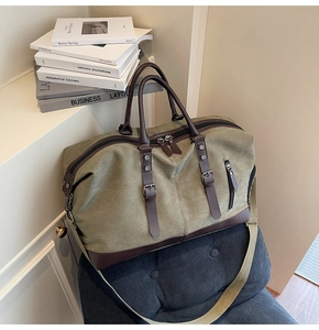 Detail of army green travel bag with brown leather handles and canvas strap on navy cushion