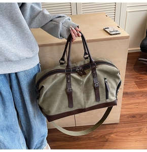 Detail of army green canvas travel bag with premium brown leather handles and stitching