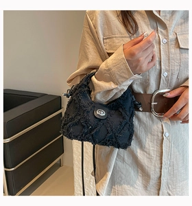 Dettaglio borsa in denim nero con trama sfrangiata e chiusura in metallo argentato