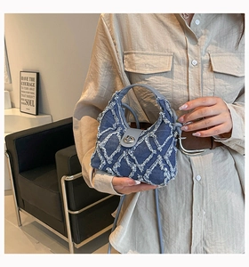 Dettaglio della mini borsa in denim con frange bianche a griglia e chiusura in metallo
