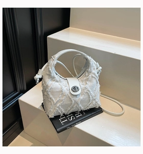 Dettaglio della borsa hobo in denim bianco con frange e chiusura in metallo argentato
