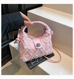 Dettaglio della borsa in denim rosa con frange e chiusura a girello in metallo argentato
