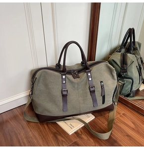 Detail of army green canvas travel bag with brown leather accents and metal buckles
