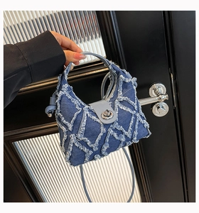 Vista dettagliata della borsa in denim blu con bordi sfrangiati e chiusura a girello