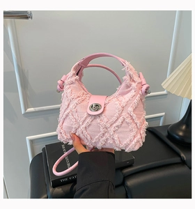 Dettaglio borsa dumpling in denim rosa con trapuntatura sfrangiata e chiusura a girello
