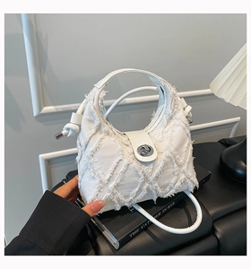 Dettaglio borsa a tracolla in denim bianco con trama a frange e chiusura a girello