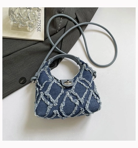 Dettaglio borsa in denim blu scuro con trapuntatura a rombi sfrangiati e chiusura argento