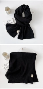 Detail of black thick knit scarf with classic vertical stripes and material care label