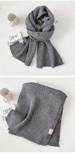 Detail of grey rib-knit scarf fabric texture and fiber content wash label on white surface