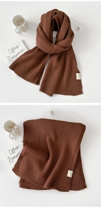 Close-up of thick dark brown knit scarf showing vertical ribbed texture and wool blend fabric