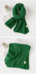 Detail of dark green ribbed knit scarf with care label and thick texture