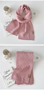 Detail des rosa Strickschals mit hohler Rautenstruktur und hochwertigem Lederetikett