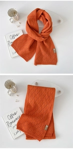 Nahaufnahme des orangefarbenen Strickschals mit filigraner Rauten-Webstruktur