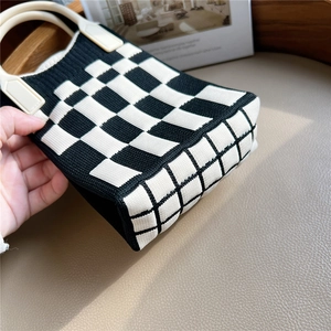 Chic black and white checkerboard knit handbag with a cream round resin handle