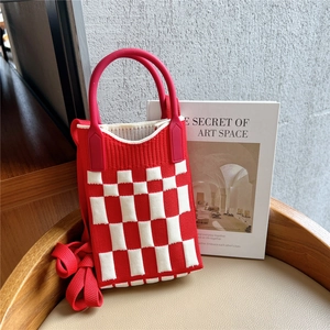 Detail of red and white checkered knit bag texture with round handles and strap