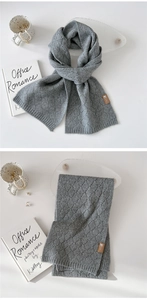 Details des grauen Strickschals mit Rautenmuster und Logo-Etikett aus Leder