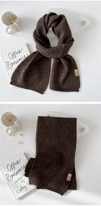 Nahaufnahme des dunkelbraunen Strickschals mit Rautenmuster und Lederlogo-Detail