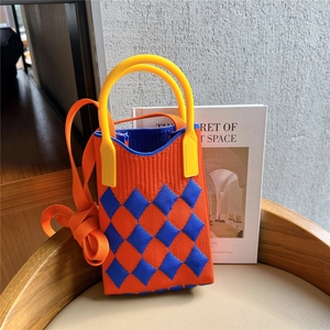 Close-up of orange and blue checkered knit mini bag with yellow handle on a chair
