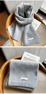 Detail of gray 100% wool knitted scarf showing soft texture and premium quality label
