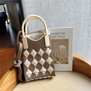 Detail of knitted plaid mini bag with cream handle and textured brown checkered fabric