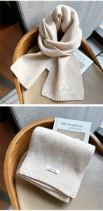Detail of oatmeal knitted wool scarf showing the 100% wool label and ribbed texture weave