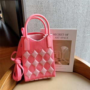 Detailed close-up of pink checkered knit mini bag with textured rhombus pattern and strap